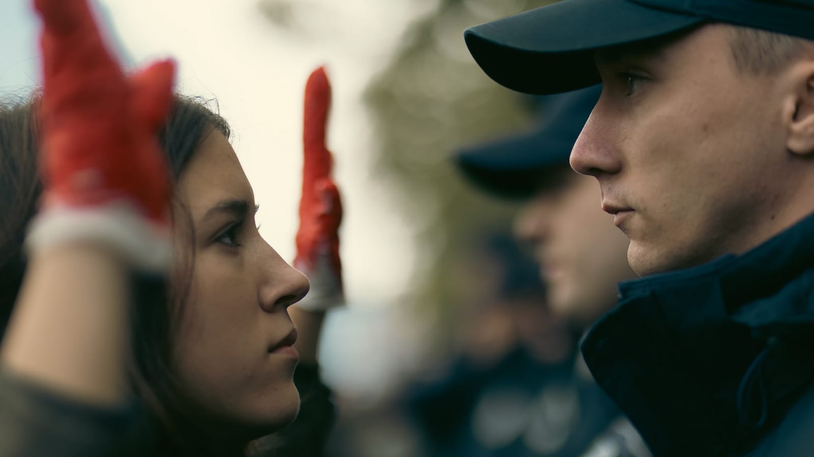 Studentkinja sa crvenim rukavicama licem u lice sa policajcem